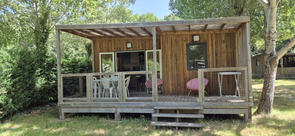 Chalet en bois avec terrasse couverte entouré d'arbres